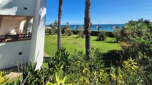 A modern building with balconies overlooking a well-maintained garden and a clear view of the ocean. - Magnificent T3 air-conditioned ground floor apartment with swimming pool and private beach ideal location (San-Nicolao)