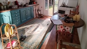 A kitchen with teal cabinets, a dining table with a floral table runner, and a view through the glass door.