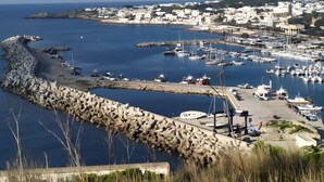 A coastal marina with boats, a rocky breakwater, and a town in the background. - Villetta Municipio - Salento Apartment with Private Terrace, Wi-Fi & Air Conditioning (Castrignano del Capo)