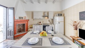 A modern kitchen with a dining area, a fireplace, and a chalkboard menu. - Villetta Municipio - Salento Apartment with Private Terrace, Wi-Fi & Air Conditioning (Castrignano del Capo)