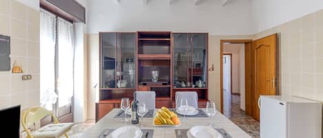 Un comedor con una mesa dispuesta para cuatro personas, un televisor y un refrigerador.