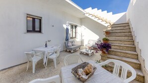 A sunlit outdoor patio with white furniture, a table with bread, and a staircase. - Villetta Municipio - Salento Apartment with Private Terrace, Wi-Fi & Air Conditioning (Castrignano del Capo)
