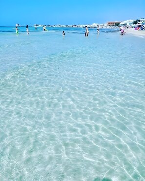 Une plage avec une eau cristalline et des personnes visibles au loin.