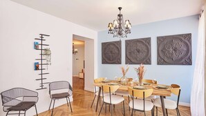 A dining area with a wooden herringbone floor, a chandelier, and a table set for four. - Superb Apartment Center of Paris (Paris)