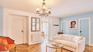 A living room with a sofa, a chair, a coffee table, a chandelier, and a mirror. - Superb Apartment Center of Paris (Paris)