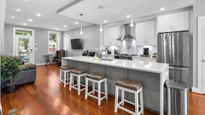 A modern kitchen with a large island, stainless steel appliances, and bar stools. - Renovated 2Level Flat+H St+Laundry (Washington)