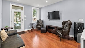 A living room with a sofa, two armchairs, a coffee table, a TV, and a water dispenser. - Renovated 2Level Flat+H St+Laundry (Washington)