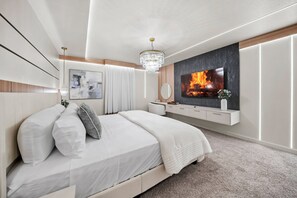Ein modernes Schlafzimmer mit einem großen Bett, einem Wand-Fernseher, einer Kristallleuchtre und einem minimalistischen Design.