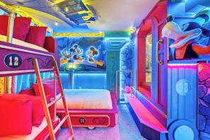 A room with bunk beds, a mural of cartoon characters, and a window with a view of the sky.