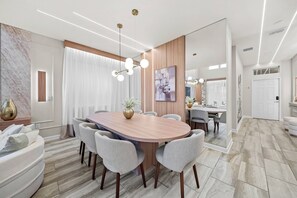 A modern dining room with a wooden table, grey chairs, and a vase of flowers.