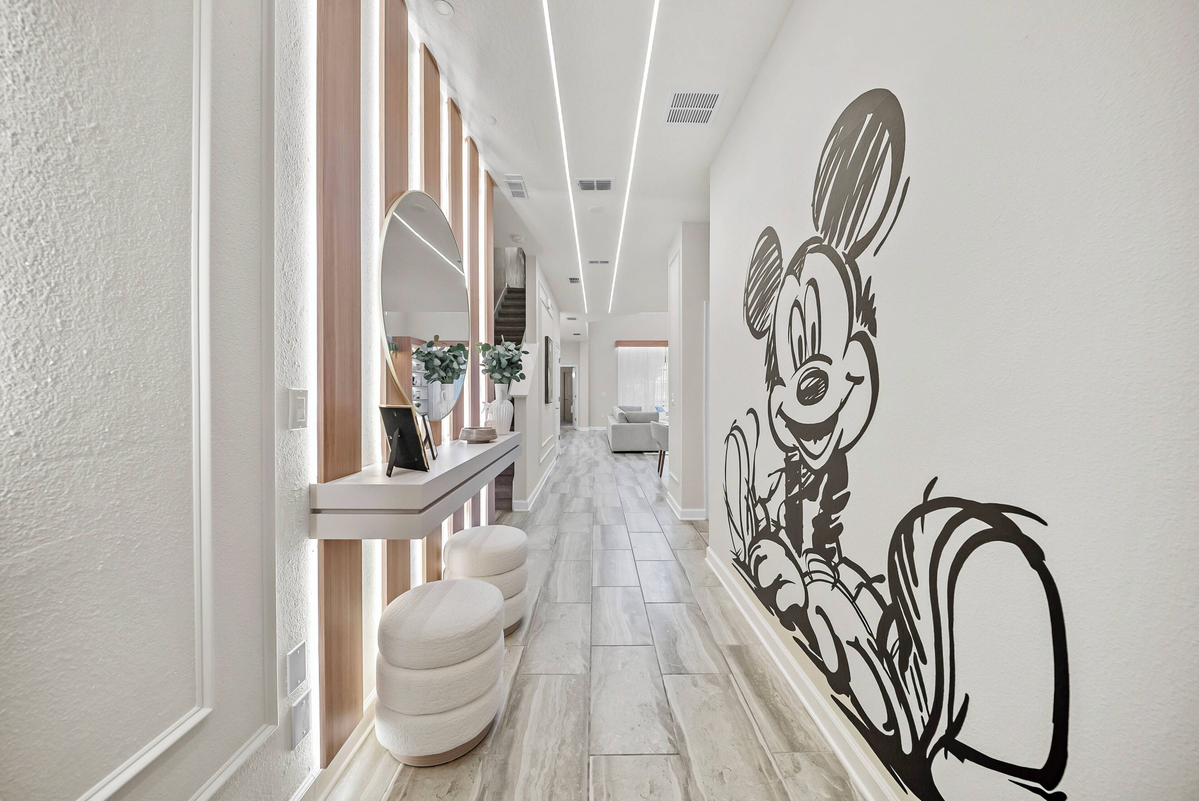 Un passadís de disseny modern, amb un mural gran a la paret, una banca i un corredor ben il·luminat.