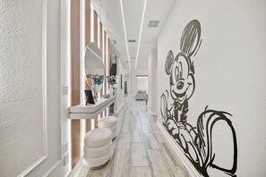 Um corredor com design moderno, apresentando um mural grande na parede, um banco e iluminação bem cuidada.