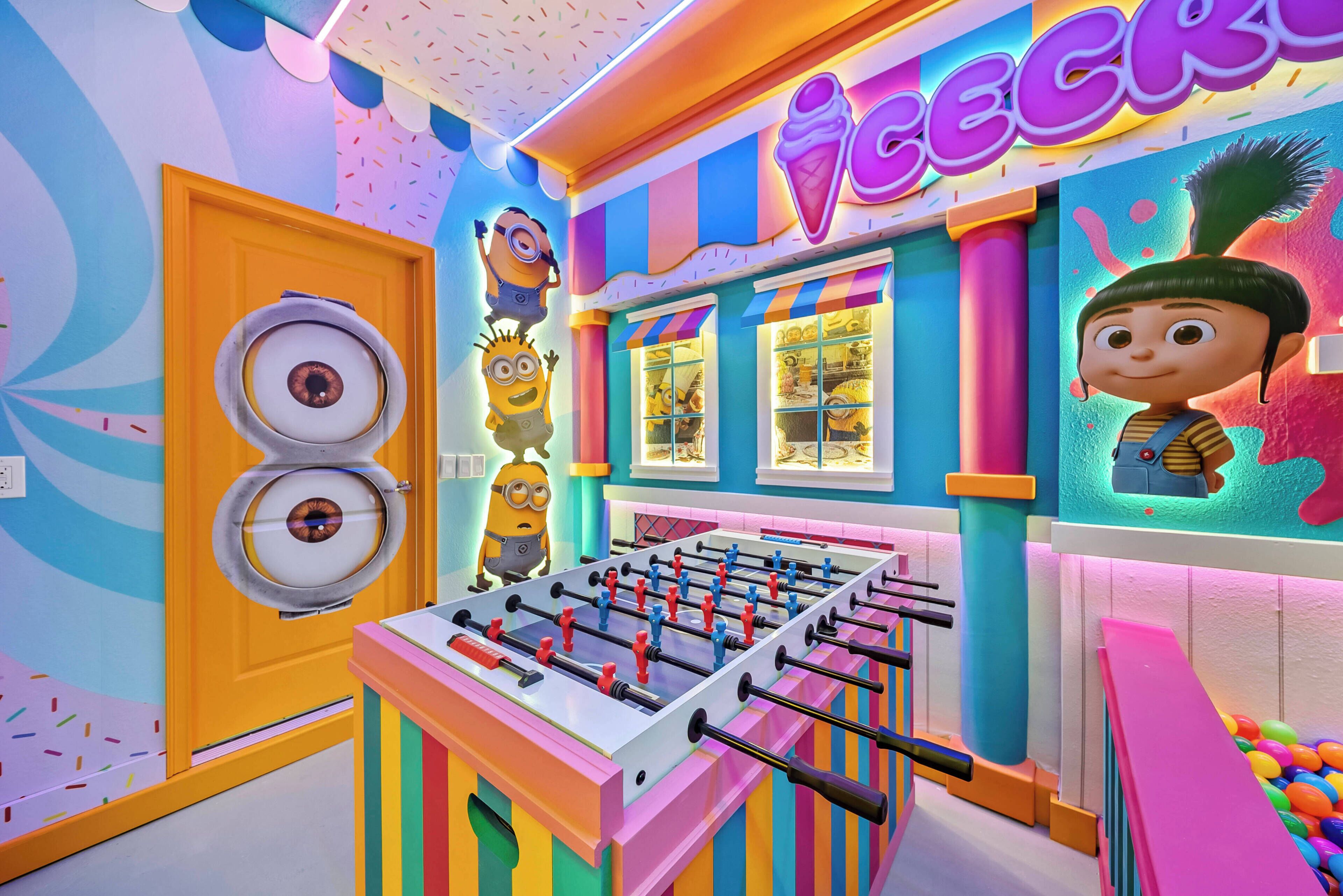 A colorful room with a foosball table, a door with a circular window, and a wall with a Minion character.