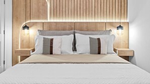 A neatly made bed with a wooden headboard, two bedside lamps, and a bedside table.