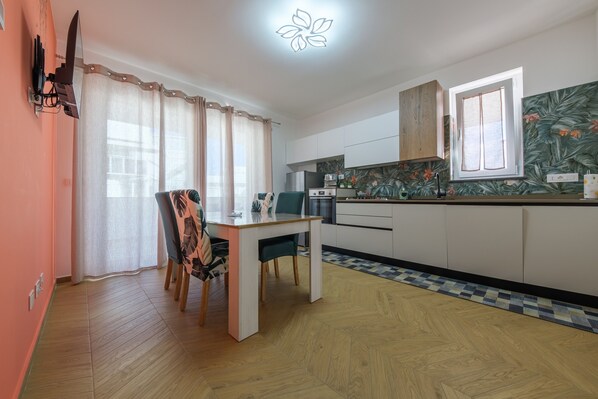 Una cocina moderna con armarios blancos, una mesa de comedor de madera y un salpicadero con diseño.