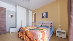 A bedroom with a bed, a nightstand, a wardrobe, and a painting on the wall. - Apartment 'Grace Home 1' with Sea View, Wi-Fi and Air Conditioning (Milazzo)