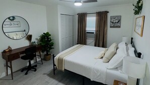 Une chambre à coucher comprenant un lit, un bureau, une chaise et un ventilateur de plafond.