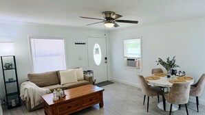 Un salon comprenant un canapé, une table basse, une table à manger avec des chaises et un ventilateur de plafond.