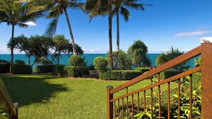 A well-maintained garden with palm trees and a wooden fence, leading to a view of the ocean. - Bangalow - Best View in Port Douglas (Port Douglas)