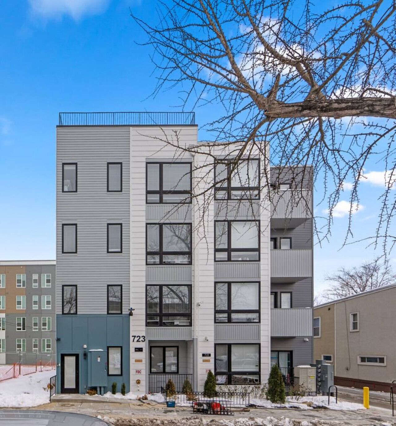 A multi-story residential building with a modern design, featuring large windows and a flat roof.