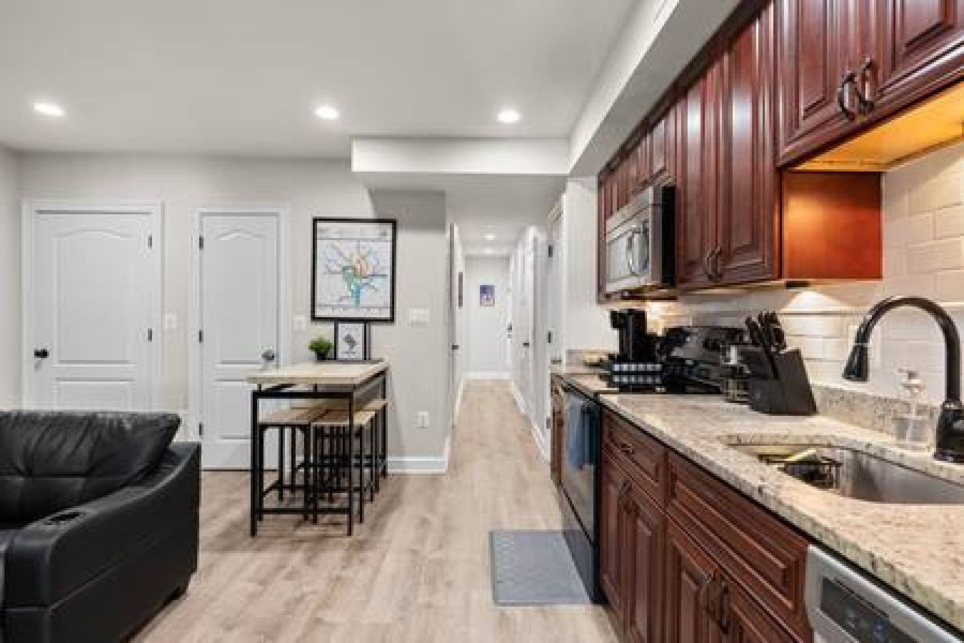 A modern kitchen with wooden cabinets, a built-in oven, and a stainless steel sink.