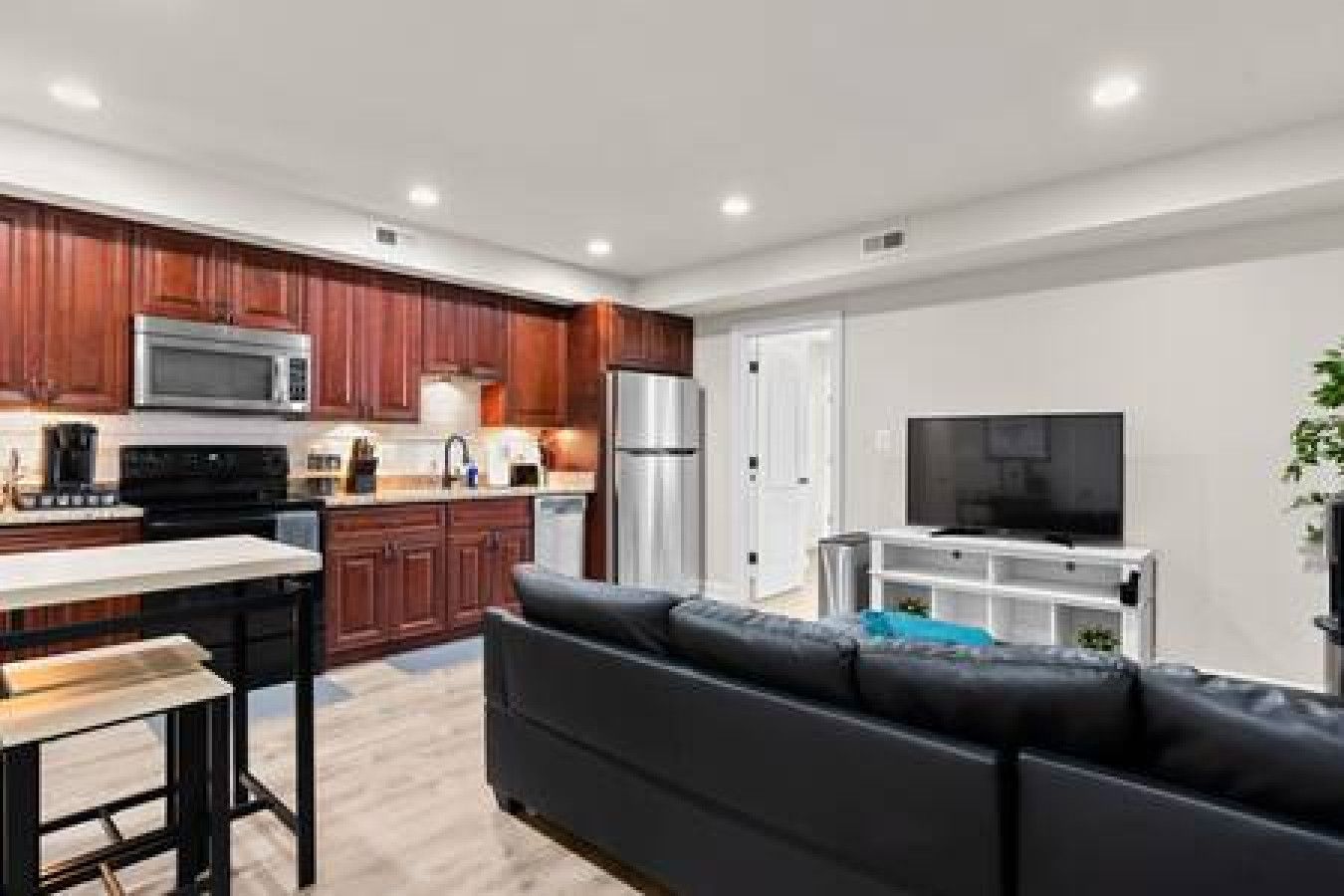 A modern kitchen with dark wooden cabinets, a stainless steel refrigerator, and a microwave.