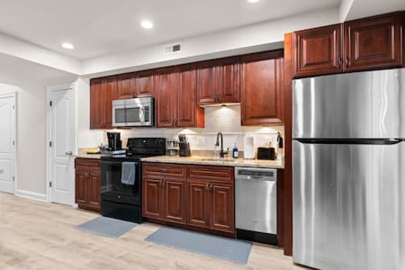 Una cocina moderna con gabinetes de madera, electrodomésticos de acero inoxidable y una estufa negra.