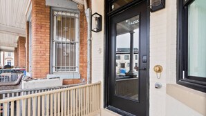 Un immeuble avec une porte noire, une fenêtre ornée de barreaux et un balcon doté d’une balustrade.