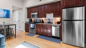 A modern kitchen with dark wood cabinets, stainless steel appliances, and a granite countertop.
