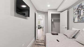 A modern bedroom with a bed, a flat-screen TV mounted on the wall, and a walk-in closet.