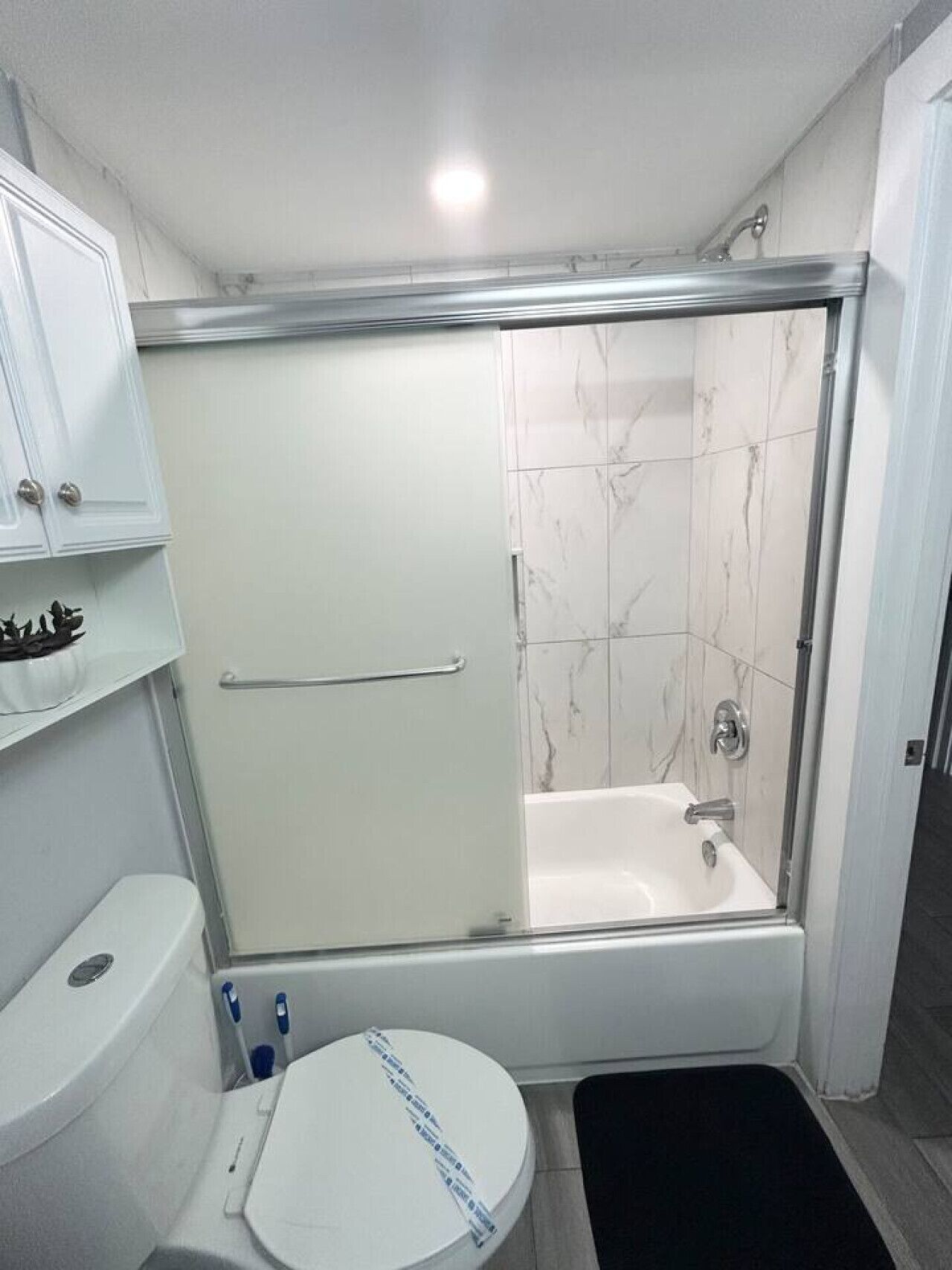 A bathroom with a glass-enclosed shower, a toilet, and a sink.
