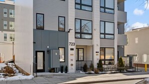 A modern multi-story building with a flat roof, large windows, and a visible entrance with a door and steps. - New DC Unit+Prime Location+2BR+Private Parking (Washington)