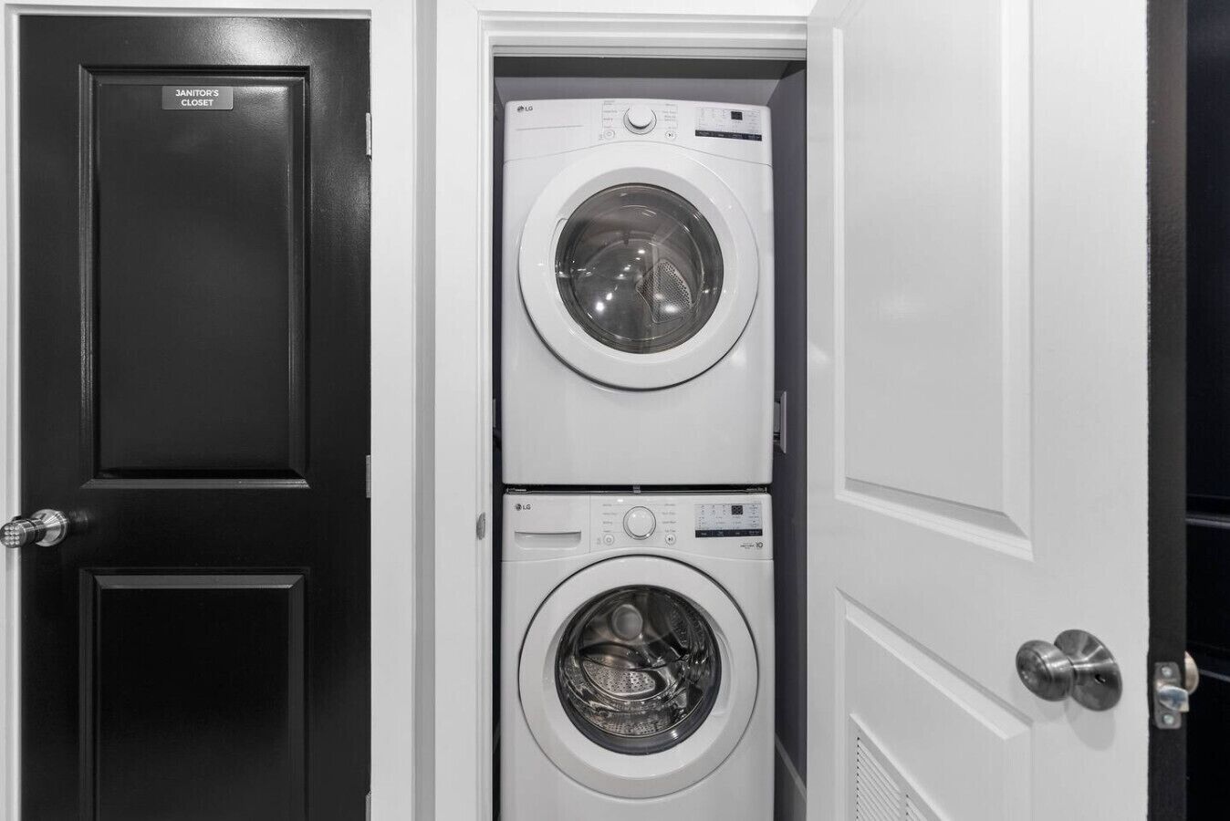 Un cuarto de lavandería con dos lavadoras apiladas y una puerta que dice 'Almacén del conserje'.
