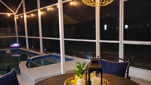 A round table with chairs, a hanging light fixture, and a view of a swimming pool. - WaterView 4 miles to Disney 3Br 2Ba Pool Home (Kissimmee)