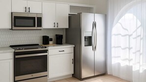A modern kitchen with white cabinetry, a stainless steel refrigerator, a microwave, and a stove. - WaterView 4 miles to Disney 3Br 2Ba Pool Home (Kissimmee)