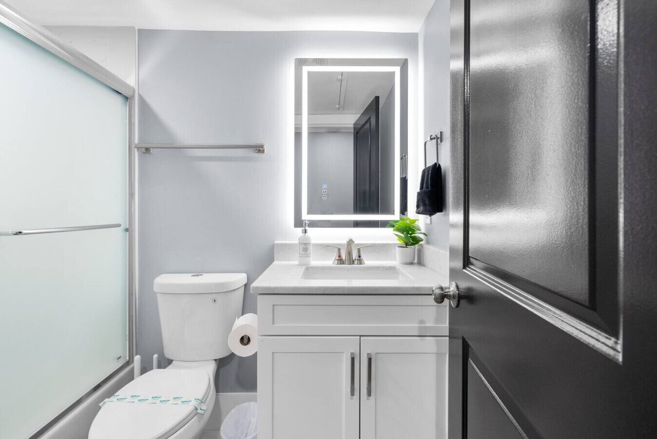 Un baño moderno con inodoro, lavabo, espejo y armarios.