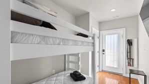 A bunk bed room with a door leading to a balcony.