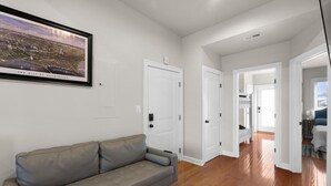 A spacious living area with a grey sofa, white doors, and a framed cityscape picture on the wall.