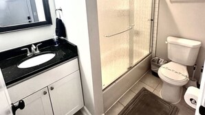 A bathroom with a white sink, a mirror, a toilet, and a shower with a glass door.