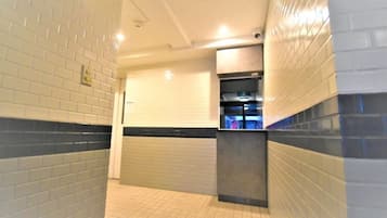 A corridor with tiled walls, a tiled floor, and a counter with a sink.