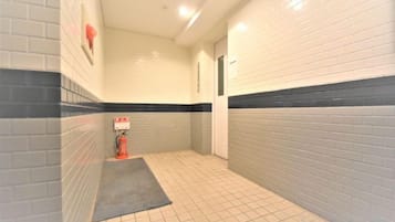 A narrow hallway with tiled walls, a fire extinguisher, and a door.