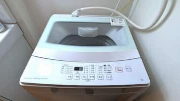 A front view of a washing machine with control panel and water inlet hose.