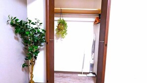 A doorway leading to a room with a potted plant, a hanging plant, and a vacuum cleaner. - KIYAZA Station Sapporo 2 (Sapporo)