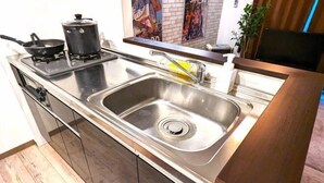 A modern kitchen with a stainless steel sink, a stove, and a pot. - KIYAZA Station Sapporo 2 (Sapporo)