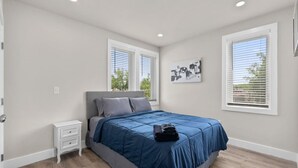 Ein Schlafzimmer mit Bett, Nachttisch und einem Kunstwerk an der Wand.