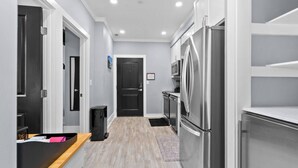 Une cuisine moderne dotée d’appareils électroménagers en acier inoxydable, d’un plan de travail en bois et d’une porte noire en arrière-plan.