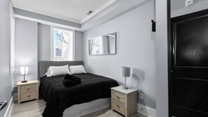 Une chambre à coucher moderne avec un lit, des tables de chevet, un miroir et une porte.