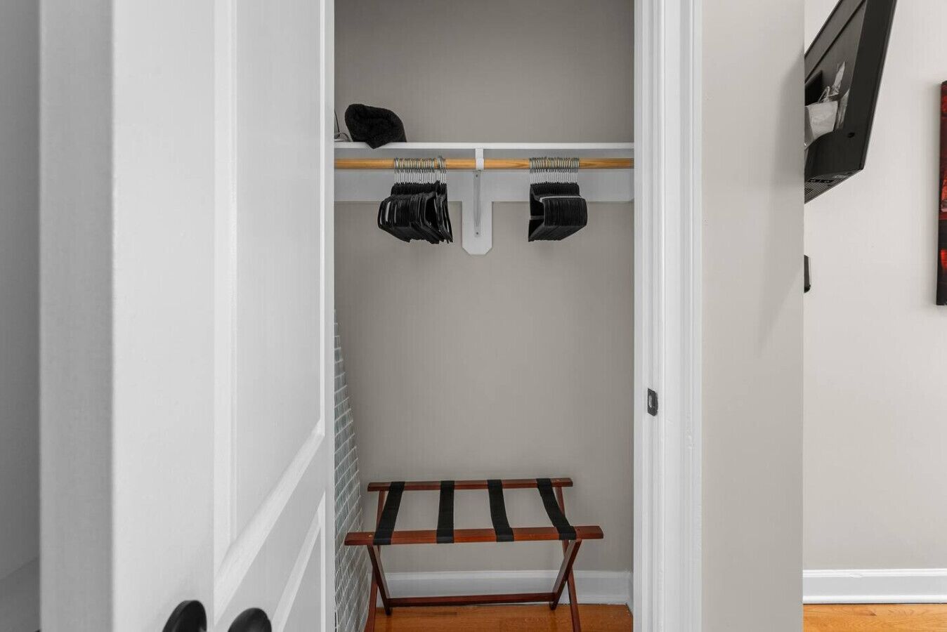 Un couloir avec un porte-chaussures, un porte-manteau et un banc en bois.