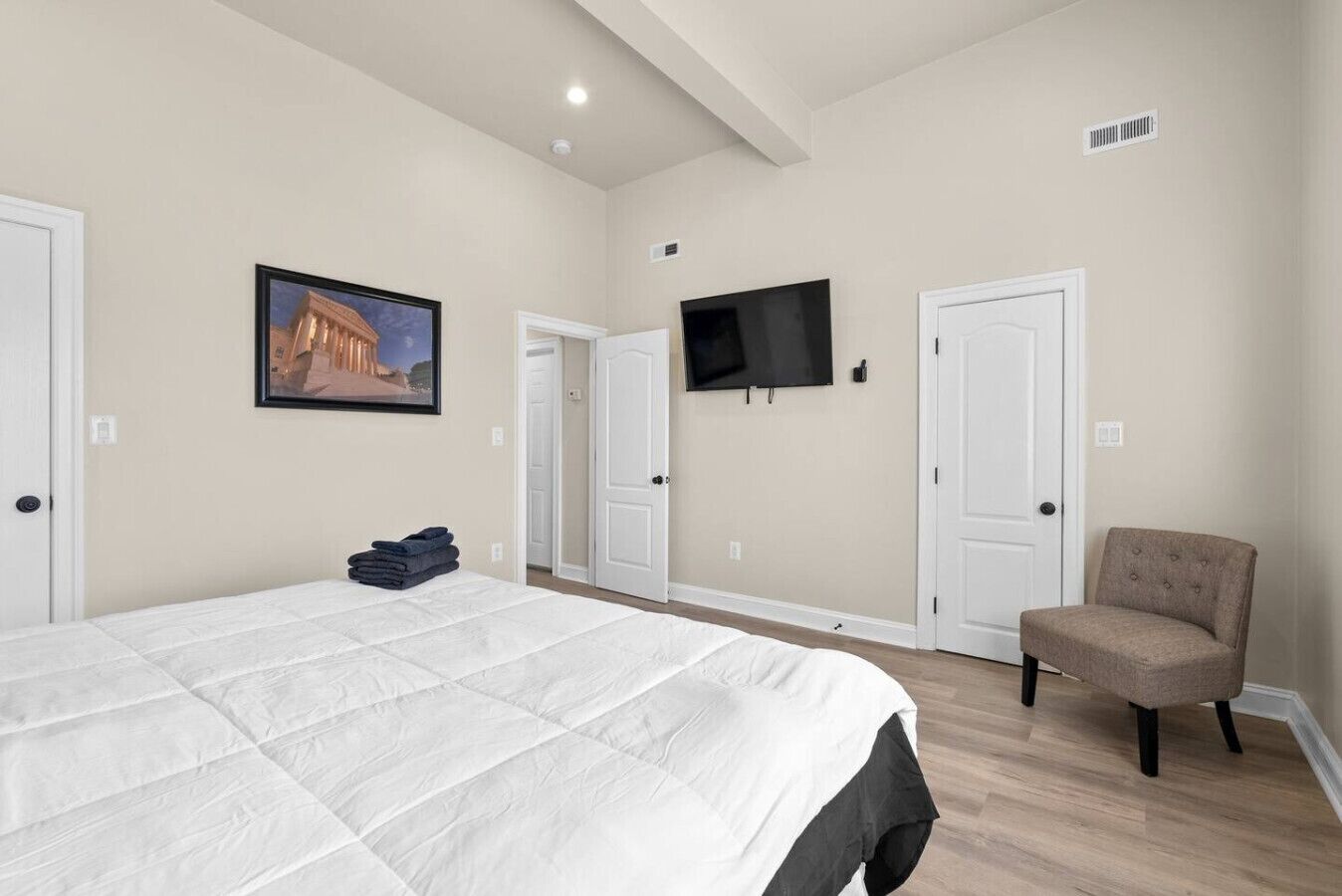 A bedroom with a large bed, a television, and a chair.