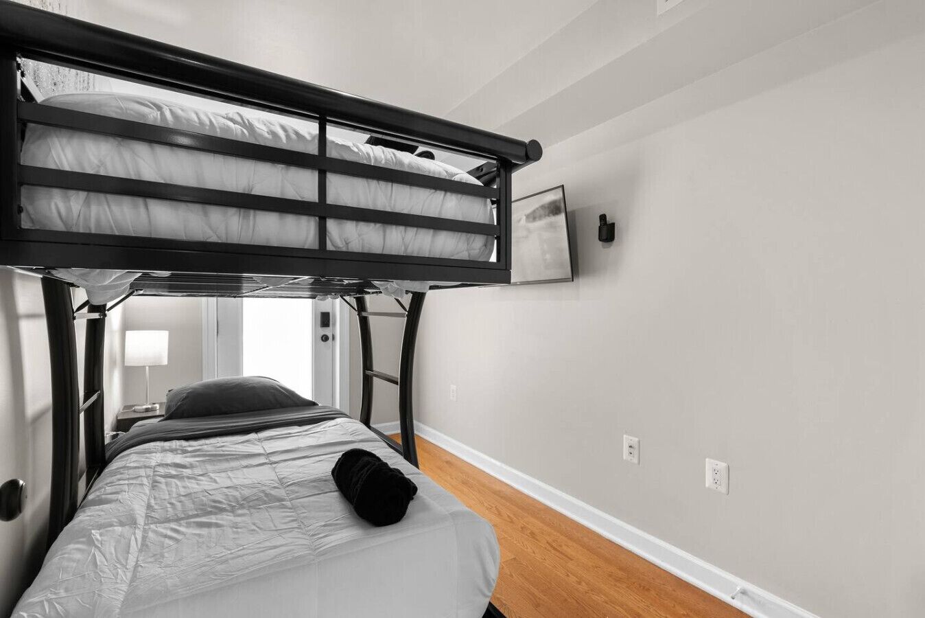 Een slaapkamer met een stapelbed, inclusief een enkel bed beneden en een bed bovenop. Er hangt een televisie aan de muur boven het bovenbed.